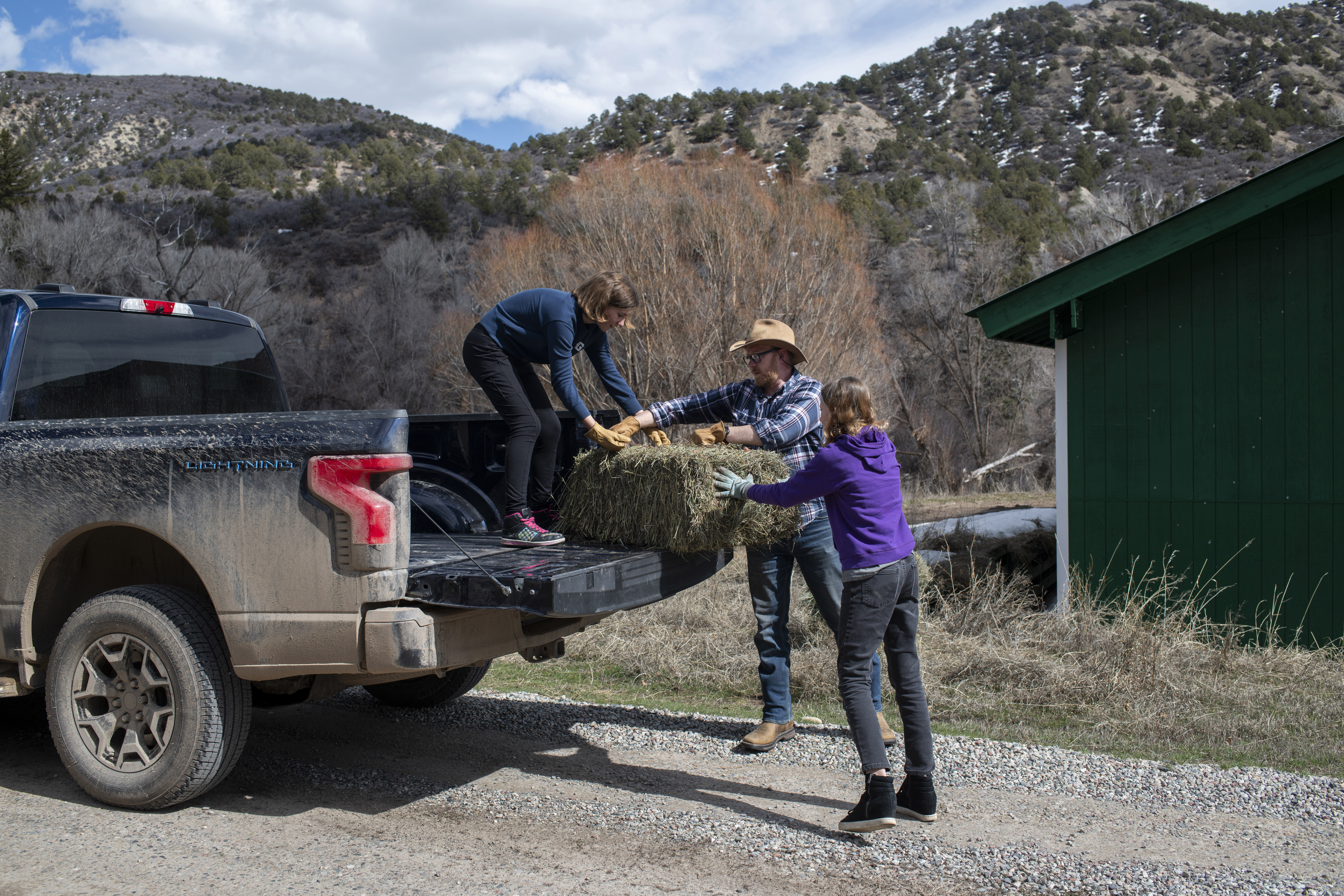 Ben Westby, center, lifts bales of hay with his daughters, Ari Westby, 12, left, and Lizzie Westby, 13, right, into the bed of their Ford F-150 Lightning on Sunday, March 17, 2024 in New Castle, Colorado. Rachel Woolf for Ford
